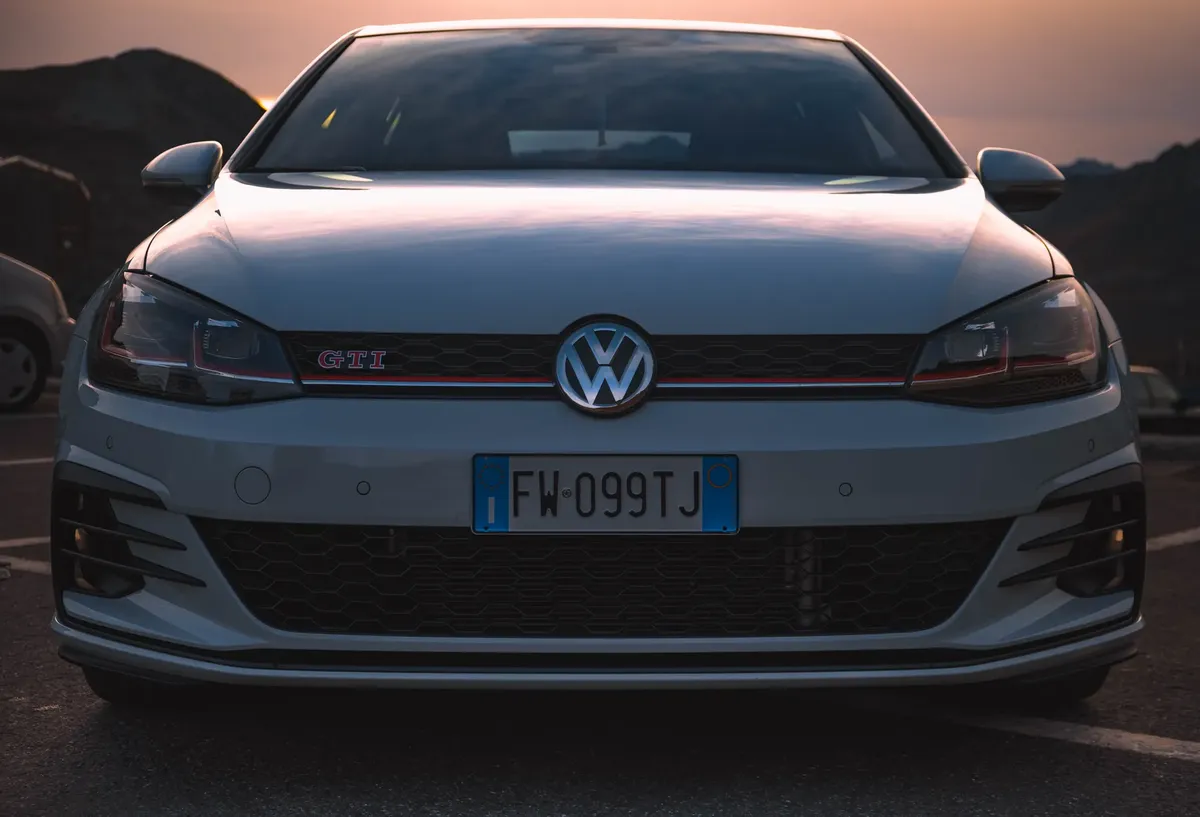 Volkswagen Golf GTI 朝前觀看，停放在戶外夕陽下，展現其流線型設計。