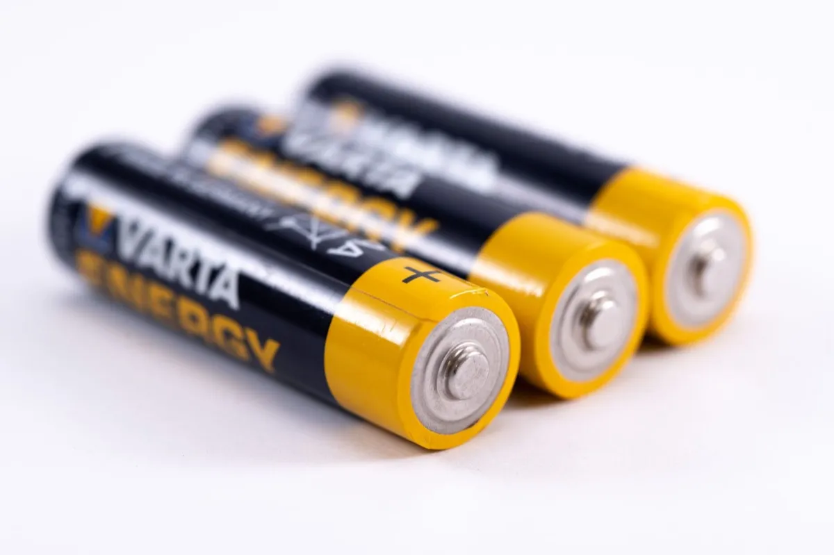 Tres pilas cilíndricas negras y amarillas con la marca Varta Energy visible reposan inclinadas sobre un fondo blanco, mostrando sus polos metálicos plateados.