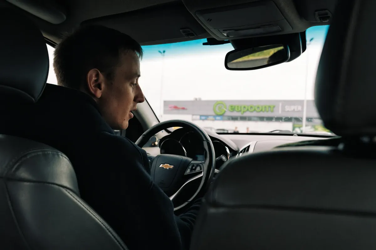 View from inside a car with a driver against a backdrop of a shopping center in Novoyelnya, Belarus.